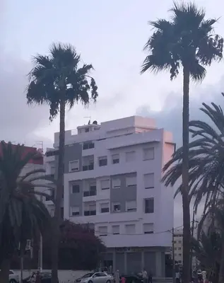 a large white building with palm trees in front of it at Champs Elysee in Casablanca