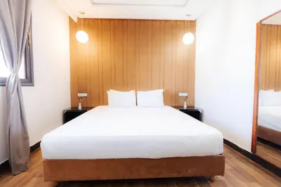 a bedroom with a large white bed and a wooden wall at WINDSOR HOTEL CITY CENTER in Casablanca