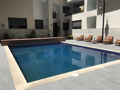 a swimming pool with chairs next to a building at Appartement Miramar in Mohammedia