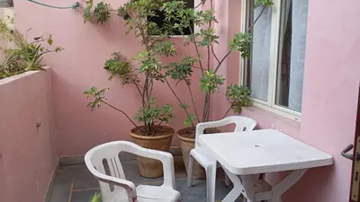 a white table and chairs in front of a pink wall at Faridi vacancy appartment in Casablanca