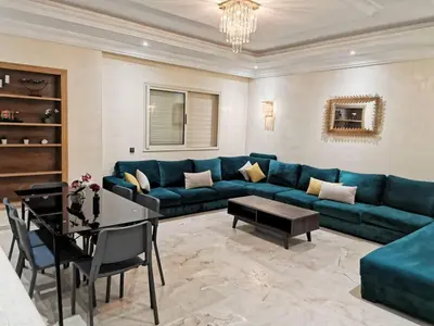 a living room with a blue couch and a table at Magnifique Villa a Savannah Beach in Sidi Rahal