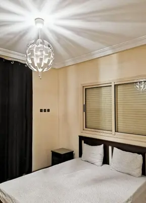 a bedroom with a large bed and a chandelier at Magnifique Villa a Savannah Beach in Sidi Rahal