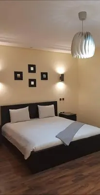 a bedroom with a large bed and a large light fixture at Magnifique Villa a Savannah Beach in Sidi Rahal