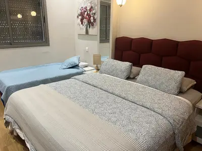 two beds in a bedroom with blue and white sheets at Hadil Room in Rabat