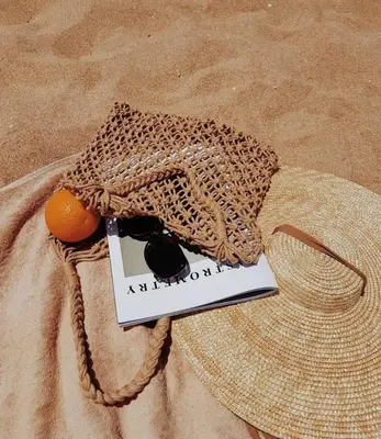 a book and an orange in a bag next to a hat at Charmant Appartement avec une vue imprenable in Tamaris