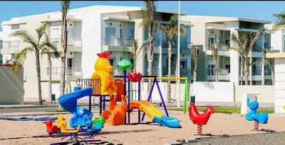 a playground in the sand in front of a building at CASA BAY BEACH RETREAT in Sidi Rahal