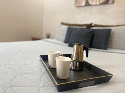 a tray with two cups and a coffee maker on a bed at Appartement près de Novotel face au parc WELCOME STAY in Mohammedia