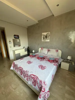 a bedroom with a bed with a red and white bedspread at Sea View Luxury Apartment Just Steps from the beach in Bouznika