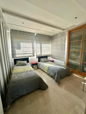 two beds sitting in a room with windows at Sea View Luxury Apartment Just Steps from the beach in Bouznika