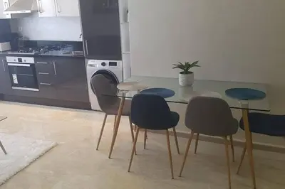 a kitchen with four chairs and a table with a counter at A 200m de la Plage, du Haut Standing au coeur du Parc in Mohammedia