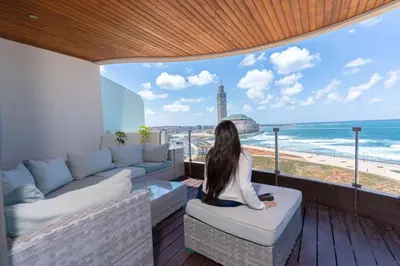 a woman sitting on a balcony looking out at the beach at KEEP CALM AND THINK OF THE SEA, MARINA!! in Casablanca