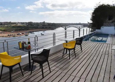 a table and chairs on a deck with a view of a river at L'Oum Errebia in Azemmour