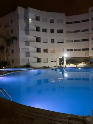 a swimming pool in front of a building at night at Jnane dalia in Bouznika