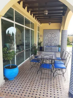 a patio with chairs and a table and a potted plant at Riad TANJIL in Casablanca