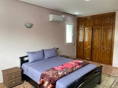 a bedroom with a bed and a wooden cabinet at Luxury Villa at Ain-Diab in Casablanca