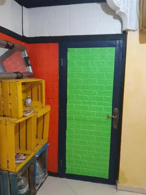 a green door in a room with a red wall at Aznavour room in Casablanca