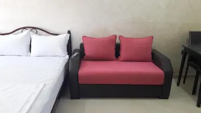 a chair with two pink pillows sitting next to a bed at Silia Appartements in Temara