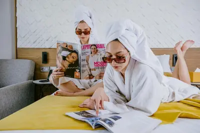 two women sitting on a bed reading a magazine at New Hotel Piscine Wellness & Spa in Casablanca