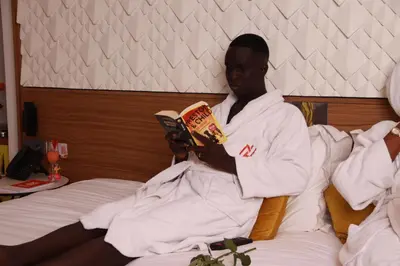 a man sitting on a bed reading a book at New Hotel Piscine Wellness & Spa in Casablanca