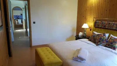 a bedroom with a large white bed with a yellow stool at Palmeraie skhirat1 in Skhirat