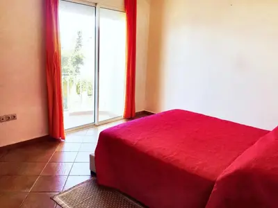 a bedroom with a red bed and a large window at Elegant villa in Dar Bouazza with year-round private pool in Dar Bouazza