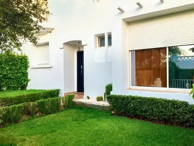 a white house with a black door and green grass at Elegant villa in Dar Bouazza with year-round private pool in Dar Bouazza