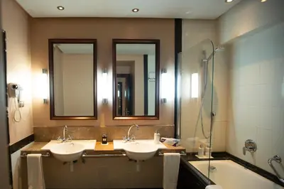 a bathroom with two sinks and a shower with mirrors at Hotel Atlantic Agdal in Rabat