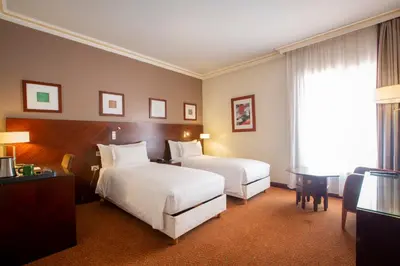 a hotel room with two beds and a desk at Hotel Atlantic Agdal in Rabat