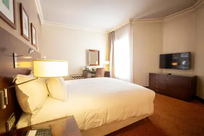 a bedroom with a large white bed and a television at Hotel Atlantic Agdal in Rabat