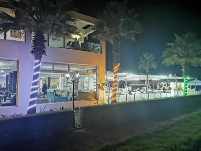 a building with palm trees in front of it at night at Magnifique Appart a Savannah Beach in Sidi Rahal