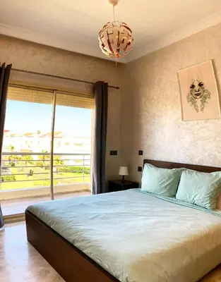 a bedroom with a large bed and a large window at Magnifique Appart a Savannah Beach in Sidi Rahal