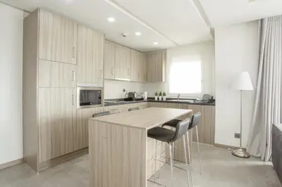 a kitchen with wooden cabinets and a island with bar stools at Makass Appart Hotel in Rabat