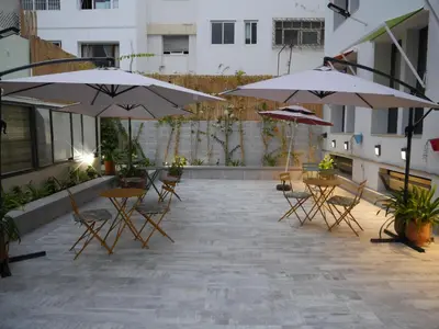 a patio with tables and chairs and umbrellas at Gardenia Boutique Hotel in Rabat