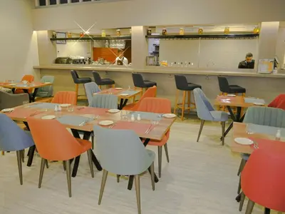 a dining room with tables and chairs and a kitchen at Gardenia Boutique Hotel in Rabat