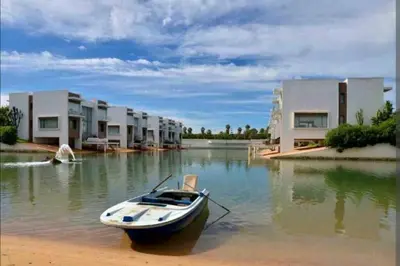 a boat sitting in the water in front of houses at Appt BOUZNIKA EDEN ISLAND pied sur Mer pour FAMILLE et Couple MARIE in Bouznika