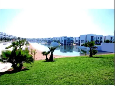 a view of a resort with palm trees and buildings at Appt BOUZNIKA EDEN ISLAND pied sur Mer pour FAMILLE et Couple MARIE in Bouznika