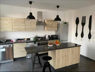 a kitchen with wooden cabinets and a black counter top at Appt BOUZNIKA EDEN ISLAND pied sur Mer pour FAMILLE et Couple MARIE in Bouznika