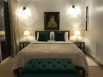 a bedroom with a large bed with a green ottoman at Palmeraie skhirat 2 in Skhirat