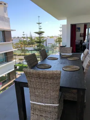 a dining table and chairs with a view of a building at Eden Island Apartment with a View in Sidi el Haj Bou Derbala