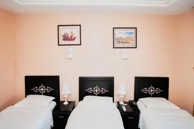 a room with two beds and two pictures on the wall at Hôtel Texuda in Rabat