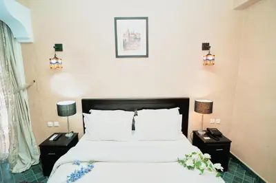 a bedroom with a bed and two night stands with lamps at Hôtel Texuda in Rabat