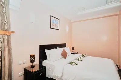 a bedroom with a bed with white sheets and pillows at Hôtel Texuda in Rabat