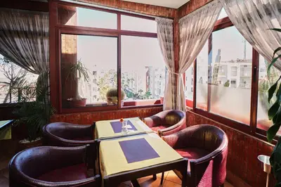 a dining room with a table and chairs and a window at Hôtel Texuda in Rabat