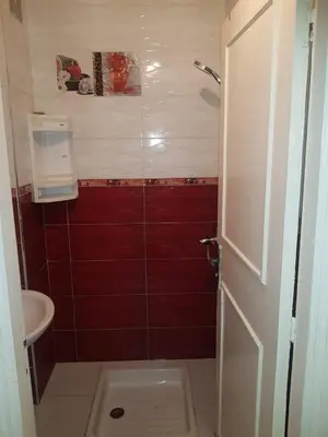 a small bathroom with a shower with red tiles at Residence Bassatine in Temara
