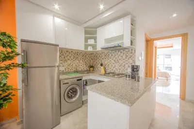 a white kitchen with a refrigerator and a dishwasher at Stayhere Rabat - Agdal 1 - Comfort Residence in Rabat