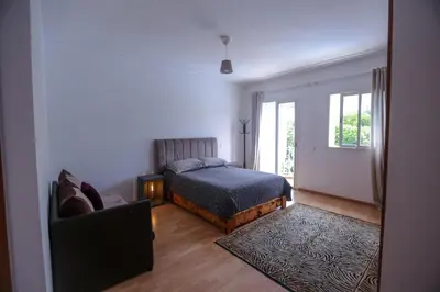 a bedroom with a bed and a couch and a window at Chez Didier Tamaris Beach in Dar Bouazza