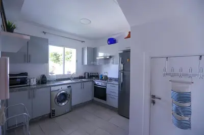 a kitchen with white cabinets and a washer and dryer at Chez Didier Tamaris Beach in Dar Bouazza