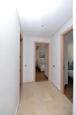 a white room with a bed and a hallway with doors at Prestigia Rabat Hay Riad Premium Apartments in Rabat
