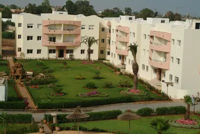 a large building with a garden in front of it at Mohammedia appart piscines in Mohammedia