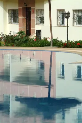 a reflection of a building in a pool of water at Mohammedia appart piscines in Mohammedia